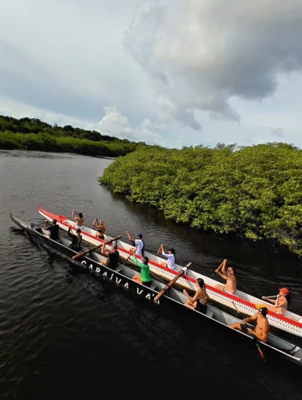 Grupo remando canoa havaiana pelo rio Caraíva